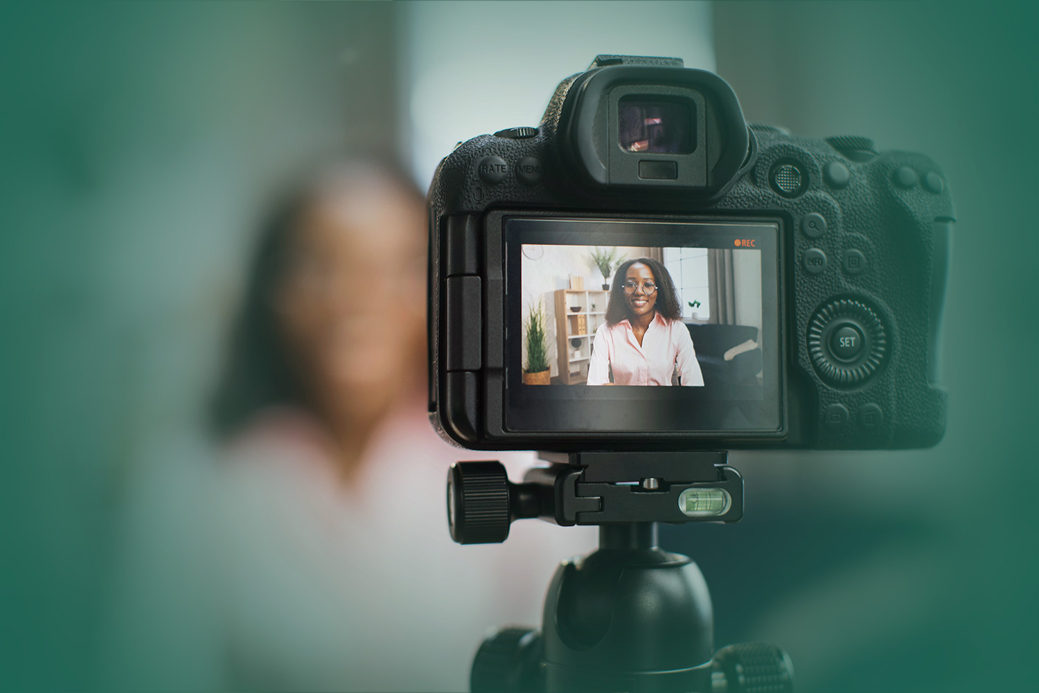 woman talking and gesturing in front of modern video camera while sitting on blur background