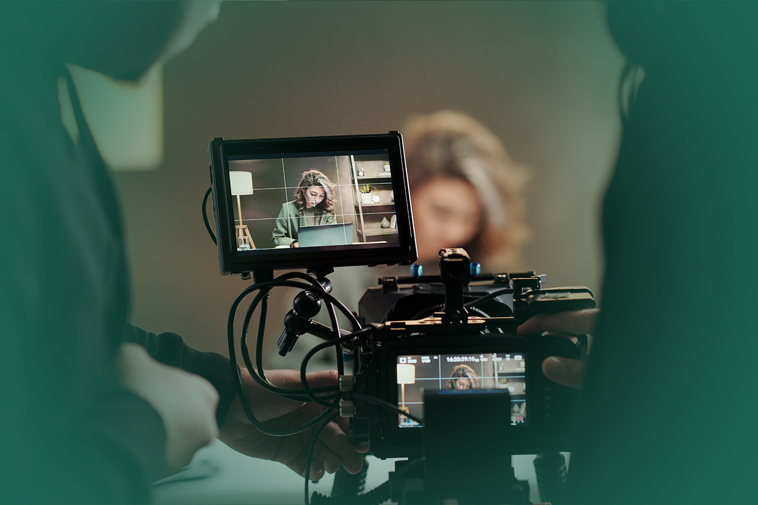 Close-up of steadicam screens with model using laptop by table